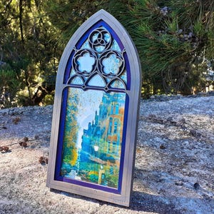 May include: A digital download of an arch frame for photos. The frame is gray with a blue and purple stained glass design. The frame is suitable for photos measuring 4x6 inches or 10x15 centimeters.