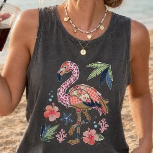 Peut inclure: Un débardeur gris anthracite sans manches avec un imprimé graphique multicolore représentant un flamant rose aux ailes à motifs, entouré d'hibiscus, d'étoiles de mer et de corail. Le haut présente une encolure ronde et une coupe décontractée.