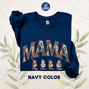 Peut inclure: Sweat-shirt bleu marine avec le mot "MAMA" dans un motif patchwork. En dessous, quatre bonhommes de neige avec des noms. Le texte "NAVY COLOR" est en bas de l'image.