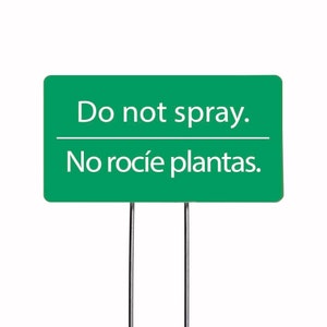 May include: Green garden sign with white text that reads "Do not spray. No rocié plantas."