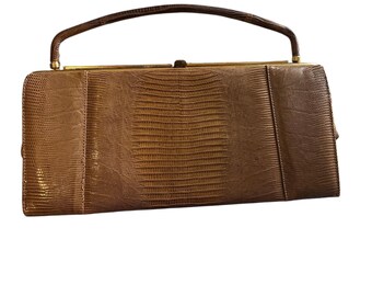 Peut inclure: Un sac à main en cuir marron avec une poignée supérieure et un fermoir doré.