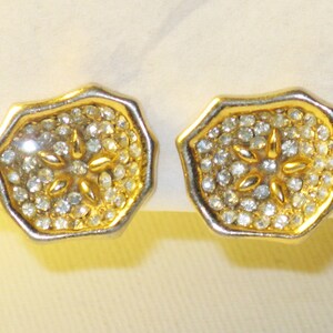 May include: A pair of gold tone earrings with a starburst design set with clear rhinestones.