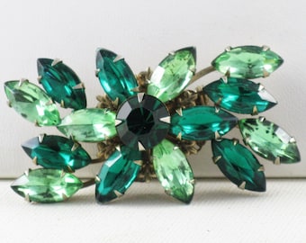 Pode incluir: Um broche vintage com um design floral com strass verdes e verde claro. O broche é feito de metal e tem um acabamento dourado.