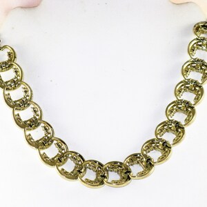 May include: A gold necklace with a chain made of interlocking oval links. Each link has a textured design.