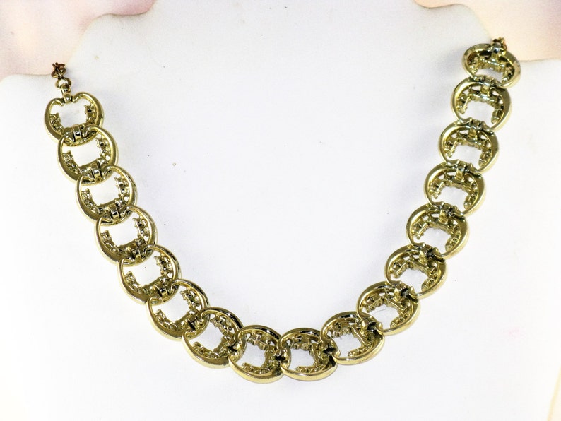 May include: A gold necklace with a chain made of interlocking oval links. Each link has a textured design.