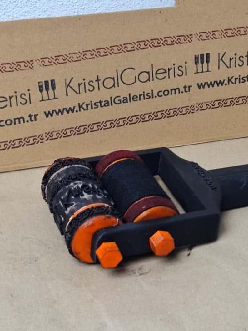 K&ouml;nnte beinhalten: Ein schwarz-oranges Dekorationsobjekt mit zwei zylindrischen Komponenten. Eine ist schwarz mit orangefarbenen Akzenten, die andere ist schwarz mit roter Oberseite. Das Objekt hat einen schwarzen Griff und orangefarbene sechseckige Details.
