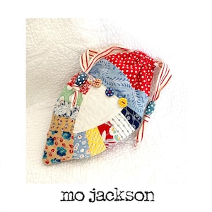 Pode incluir: Uma bolsa de cordão de tecido patchwork com um painel em forma de coração no centro. A bolsa é feita de vários tecidos coloridos, incluindo vermelho, azul, amarelo e verde. A bolsa tem um cordão branco e é decorada com botões.