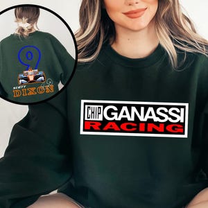 May include: Dark green sweatshirt featuring the text "CHIP GANASSI RACING" in a white and red rectangular design. The back of the sweatshirt has a circular graphic with the number 9 and the name "SCOTT DIXON".