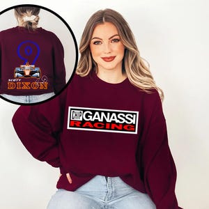 May include: A maroon sweatshirt featuring the Chip Ganassi Racing logo in a white rectangle with red accents. The back of the sweatshirt, shown in a circular inset, displays a race car graphic with the number 9 and the name "Scott Dixon."