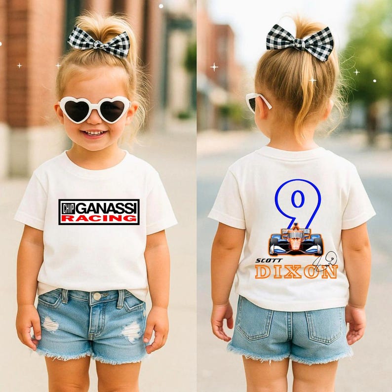 May include: A white t-shirt with "CHIP GANASSI RACING" printed on the front and a racing car design with the number "9" and "SCOTT DIXON" on the back. The child is wearing denim shorts and a black and white checkered bow.