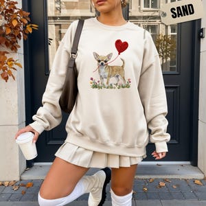 Faux Yarn Chihuahua shirt, puppy love shirt, yarn heart balloon, valentine dog tee style for tiny-dog fans. A cute Chihuahua with big ears holding a red yarn heart balloon string, finished with soft floral details for everyday wear.
