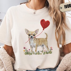 Faux Yarn Chihuahua shirt, puppy love shirt, yarn heart balloon, valentine dog tee style for tiny-dog fans. A cute Chihuahua with big ears holding a red yarn heart balloon string, finished with soft floral details for everyday wear.