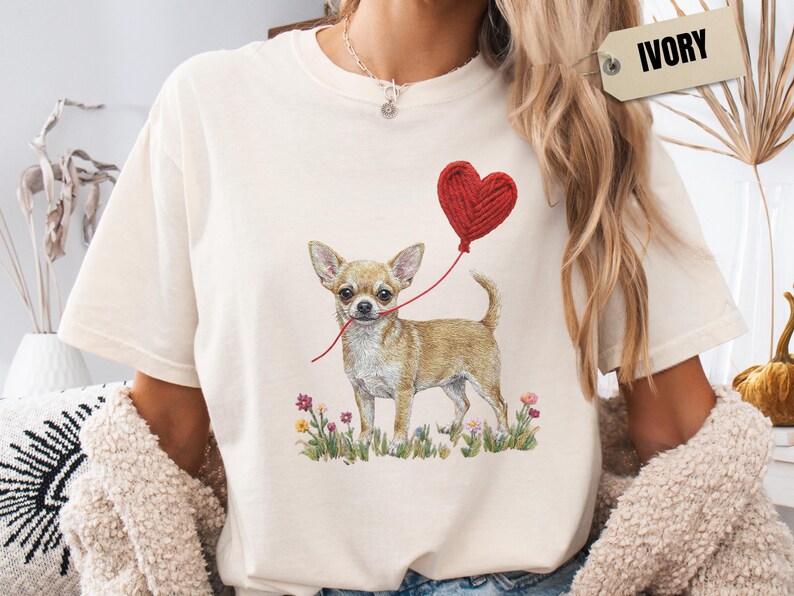 Faux Yarn Chihuahua shirt, puppy love shirt, yarn heart balloon, valentine dog tee style for tiny-dog fans. A cute Chihuahua with big ears holding a red yarn heart balloon string, finished with soft floral details for everyday wear.