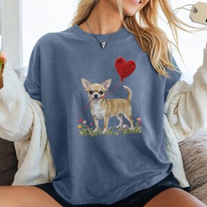Faux Yarn Chihuahua shirt, puppy love shirt, yarn heart balloon, valentine dog tee style for tiny-dog fans. A cute Chihuahua with big ears holding a red yarn heart balloon string, finished with soft floral details for everyday wear.