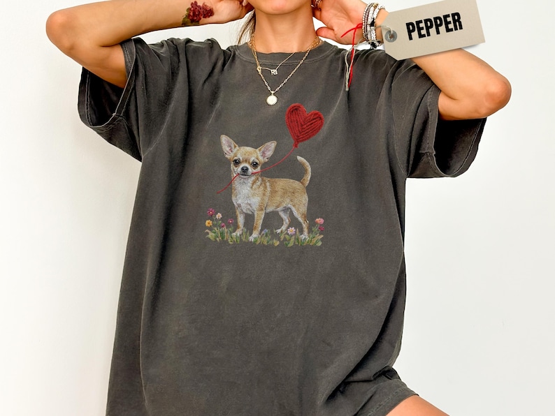 Faux Yarn Chihuahua shirt, puppy love shirt, yarn heart balloon, valentine dog tee style for tiny-dog fans. A cute Chihuahua with big ears holding a red yarn heart balloon string, finished with soft floral details for everyday wear.