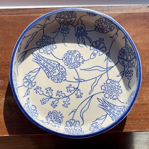 May include: A white ceramic bowl with a blue and white floral pattern. The bowl has a round shape and a blue rim.