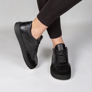 A pair of black sneakers with a low, platform sole.