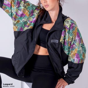 May include: Black jacket with a colorful leopard print on the sleeves. The jacket has a zipper closure and a small logo on the left chest.