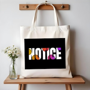 May include: White canvas tote bag with black handles. The bag has a black rectangle with the word "NOTICE" in white letters. The letters are filled with colorful circles.
