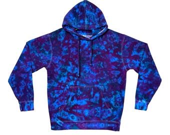 May include: A long-sleeve hooded sweatshirt featuring a tie-dye pattern in shades of deep purple, royal blue, and bright cyan. The pullover garment includes a front kangaroo pocket, a drawstring hood, and ribbed cuffs at the wrists and hemline.
