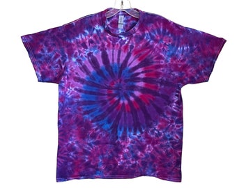 Op de afbeelding: Een tie-dye T-shirt met een draaiende print in tinten paars, roze en blauw.