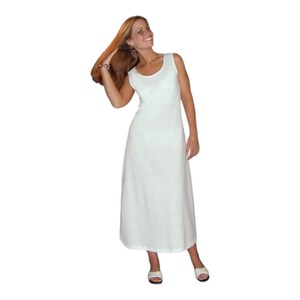 May include: A sleeveless, floor-length white dress with a scoop neckline. The dress has a simple, elegant design and is made of a lightweight fabric. The model is wearing white sandals.