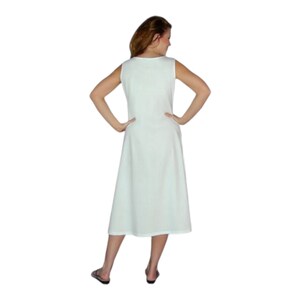 May include: A sleeveless, knee-length, light green dress. The dress has a simple, A-line silhouette and a scoop neckline. The person is wearing black sandals. The dress is made of a soft, flowing fabric.