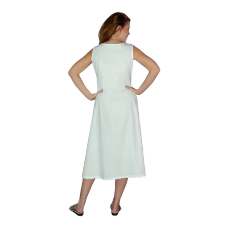 May include: A sleeveless, knee-length, light green dress. The dress has a simple, A-line silhouette and a scoop neckline. The person is wearing black sandals. The dress is made of a soft, flowing fabric.