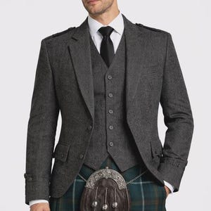 May include: A grey tweed three-piece suit with a black tie and white shirt. The outfit includes a green and blue plaid kilt and a brown leather sporran with silver detailing. The jacket has shoulder epaulettes.