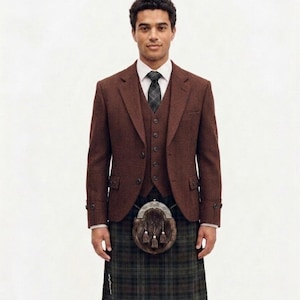 Può includere: Un completo formale composto da giacca, gilet e cravatta in tweed marrone, abbinato a un tradizionale kilt scozzese e sporran. Il kilt presenta un motivo a quadri verdi e marroni, su sfondo bianco.