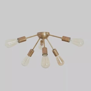 May include: A brass-toned ceiling light fitting with six Edison-style bulbs. The central hub has arms extending outwards, each holding a bulb. The bulbs are clear with a warm, amber glow. The fixture is designed for ceiling mounting.
