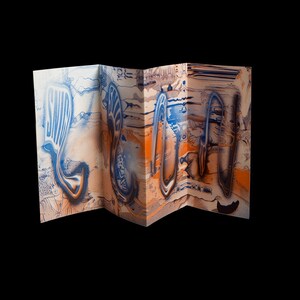 Peut inclure: Une œuvre d'art pliée en papier avec un design unique. L'œuvre présente un mélange de couleurs bleu, orange et blanc avec des formes abstraites et le mot "SNOW" dans une police stylisée. Le fond est noir.