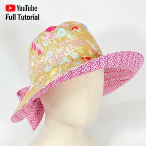 May include: A wide-brimmed sun hat with a floral print on the top and a pink and white geometric pattern on the underside of the brim.