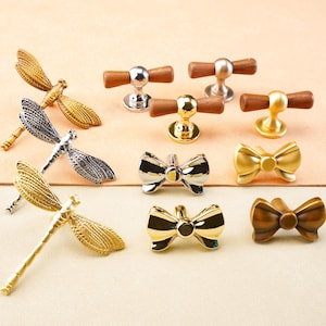 絶妙なトンボ型ノブ、キャビネットプル、クロム製ドアハンドル、ドレッサー引き出し用リボン型ノブ、ワードローブハンドル、ゴールド製食器棚ノブ、モダンな金具