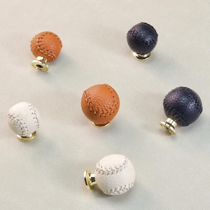 以下が含まれることがあります： 白、茶色、ネイビーブルーの野球をテーマにした6つのキャビネットノブ。 各ノブは丸く、野球のステッチパターンと金色のベースが付いています。 これらの装飾的なノブは、スポーツをテーマにした部屋に最適です。