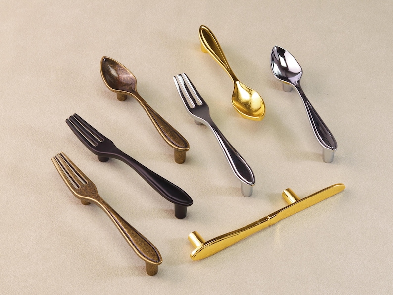 May include: A selection of decorative cabinet handles shaped like spoons and forks. The handles come in various metallic finishes, including gold, silver, and bronze. The designs are based on cutlery.