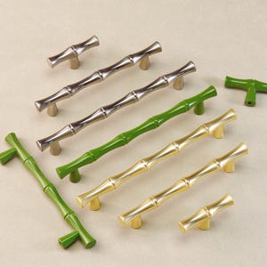 May include: An assortment of bamboo-style cabinet pulls and knobs in various finishes. The hardware includes silver, green, and gold-toned options, with a bamboo stalk design. The knobs and pulls are arranged on a neutral background.