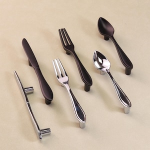 May include: A selection of cutlery-style cabinet handles. The handles include forks, spoons, and knives in silver and black finishes. These handles are designed for mounting on drawers or cabinet doors.