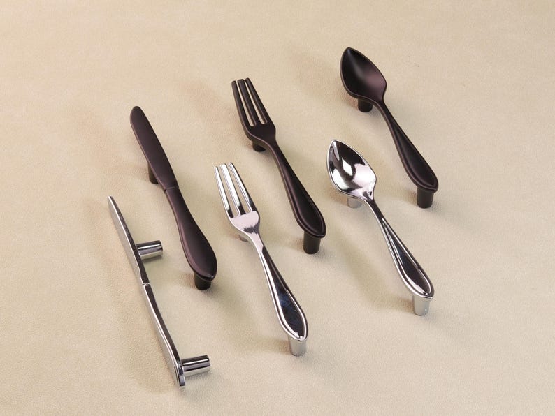 May include: A selection of cutlery-style cabinet handles. The handles include forks, spoons, and knives in silver and black finishes. These handles are designed for mounting on drawers or cabinet doors.