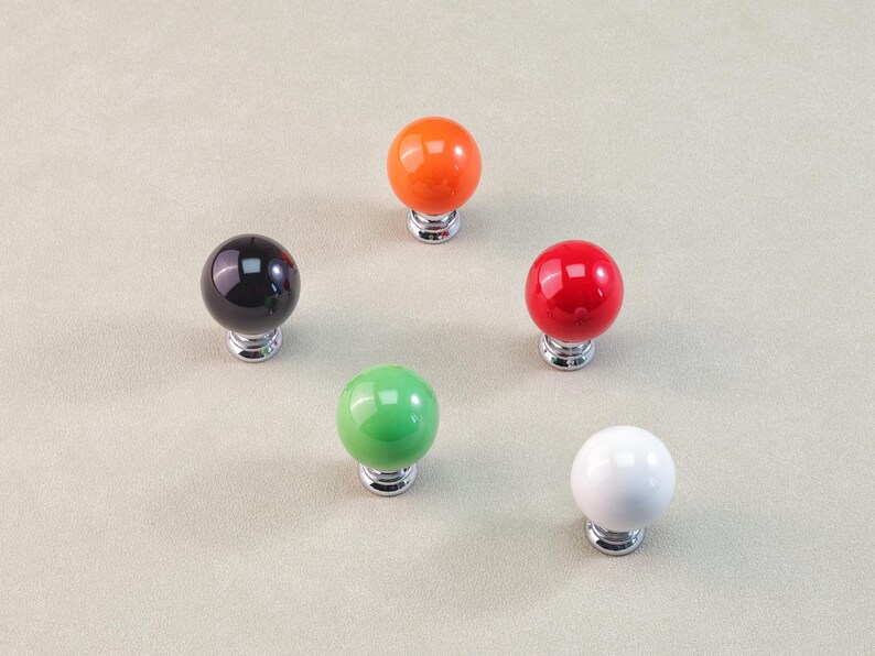 Peut inclure: Ensemble de cinq boutons de meubles sph&eacute;riques aux couleurs vari&eacute;es : noir, orange, rouge, vert et blanc. Chaque bouton a une finition brillante et est mont&eacute; sur une base argent&eacute;e. Les boutons sont dispos&eacute;s en cercle. Mesures en centim&egrave;tres.