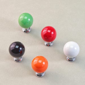 Peut inclure: Cinq boutons de meubles sph&eacute;riques de couleurs vives : vert, rouge, noir, orange et blanc. Chaque bouton a une finition brillante et une base chrom&eacute;e. Id&eacute;al pour les armoires et les tiroirs.