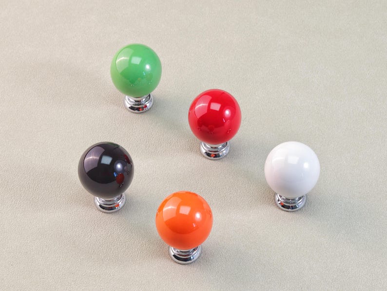 Peut inclure: Cinq boutons de meubles sph&eacute;riques de couleurs vives : vert, rouge, noir, orange et blanc. Chaque bouton a une finition brillante et une base chrom&eacute;e. Id&eacute;al pour les armoires et les tiroirs.