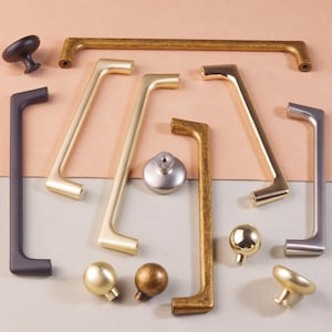 May include: Assortment of cabinet hardware in various finishes, including gold, brass, and black. The hardware includes knobs and pulls in different styles and sizes.