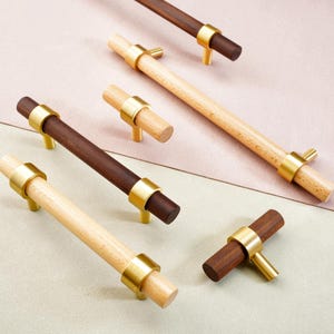 May include: A collection of wooden cabinet pulls with brass accents. Some pulls are light-colored wood, while others are dark brown. The brass hardware adds a touch of elegance to the design. These pulls are ideal for kitchen or bathroom cabinets.