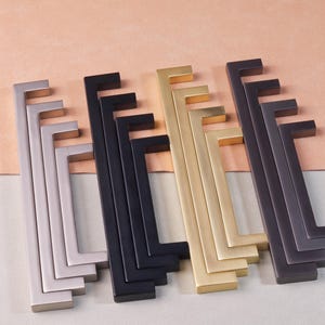 以下が含まれることがあります： 異なる仕上げのキャビネット金具が5セットあります。金具は金属製で、シンプルでモダンなデザインです。仕上げには、ブラッシュドニッケル、ブラック、ブラス、オイルラビングブロンズがあります。