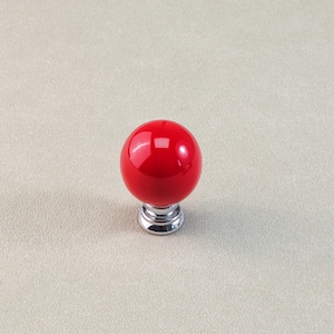 Peut inclure: Un bouton de meuble sph&eacute;rique rouge avec une finition brillante. Le bouton repose sur une base chrom&eacute;e. Ce mat&eacute;riel d&eacute;coratif convient aux tiroirs, aux armoires ou aux meubles. Le bouton mesure environ 3,8 cm de diam&egrave;tre.