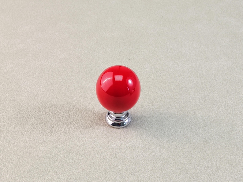 Peut inclure: Un bouton de meuble sph&eacute;rique rouge avec une finition brillante. Le bouton repose sur une base chrom&eacute;e. Ce mat&eacute;riel d&eacute;coratif convient aux tiroirs, aux armoires ou aux meubles. Le bouton mesure environ 3,8 cm de diam&egrave;tre.