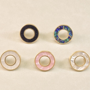 May include: Five circular cabinet knobs with a gold-coloured metal rim. The central inlays vary in colour and pattern, including black, pink, and iridescent. These decorative knobs are suitable for furniture and are measured in centimetres.