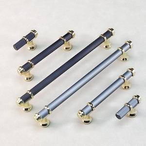 Op de afbeelding: Een collectie kastbeslag met verschillende maten stanggrepen en knoppen. De grepen en knoppen hebben een geribbelde, donkergrijze afwerking met goudkleurige accenten. Ontworpen voor gebruik op kasten en lades.