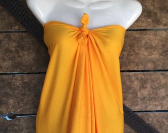 May include: A bright yellow strapless sarong tied in a knot at the front. The sarong is made of a soft, flowing fabric and is perfect for a day at the beach or pool.